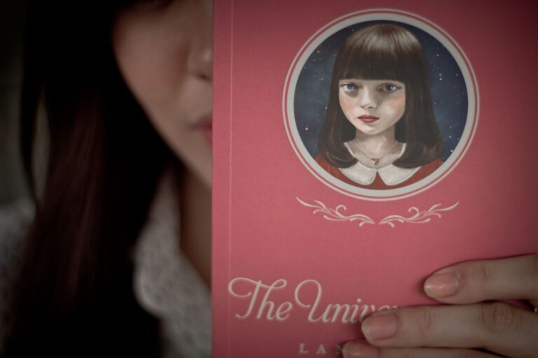 A close-up of a person holding 'The Universe of Us' by Lang Leav showcasing the book cover.