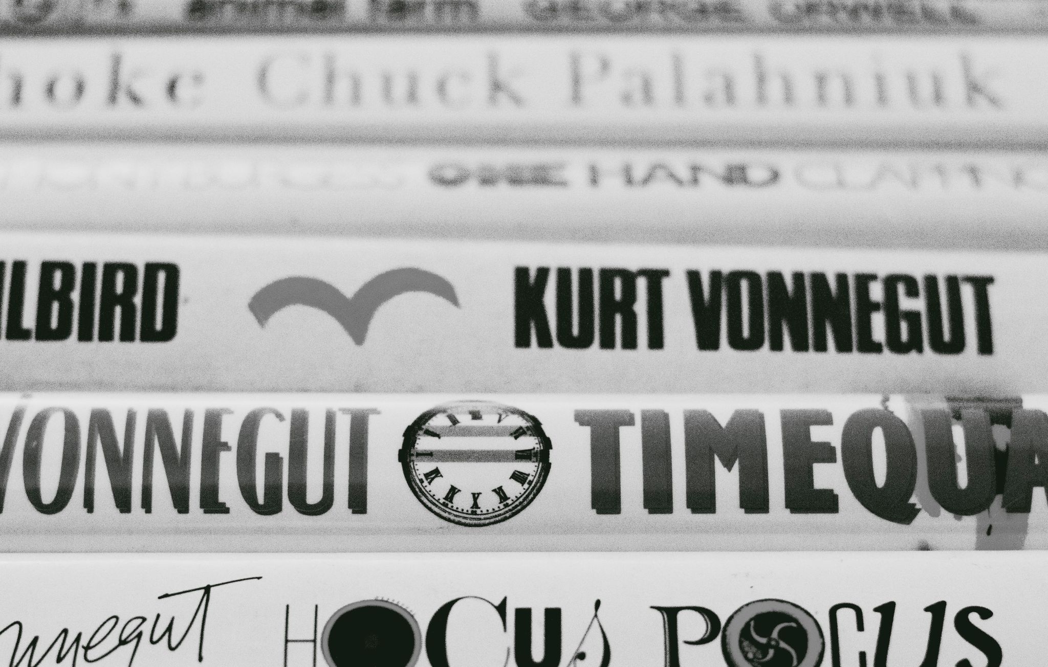 Close-up black and white photo of Kurt Vonnegut book spines on a shelf.