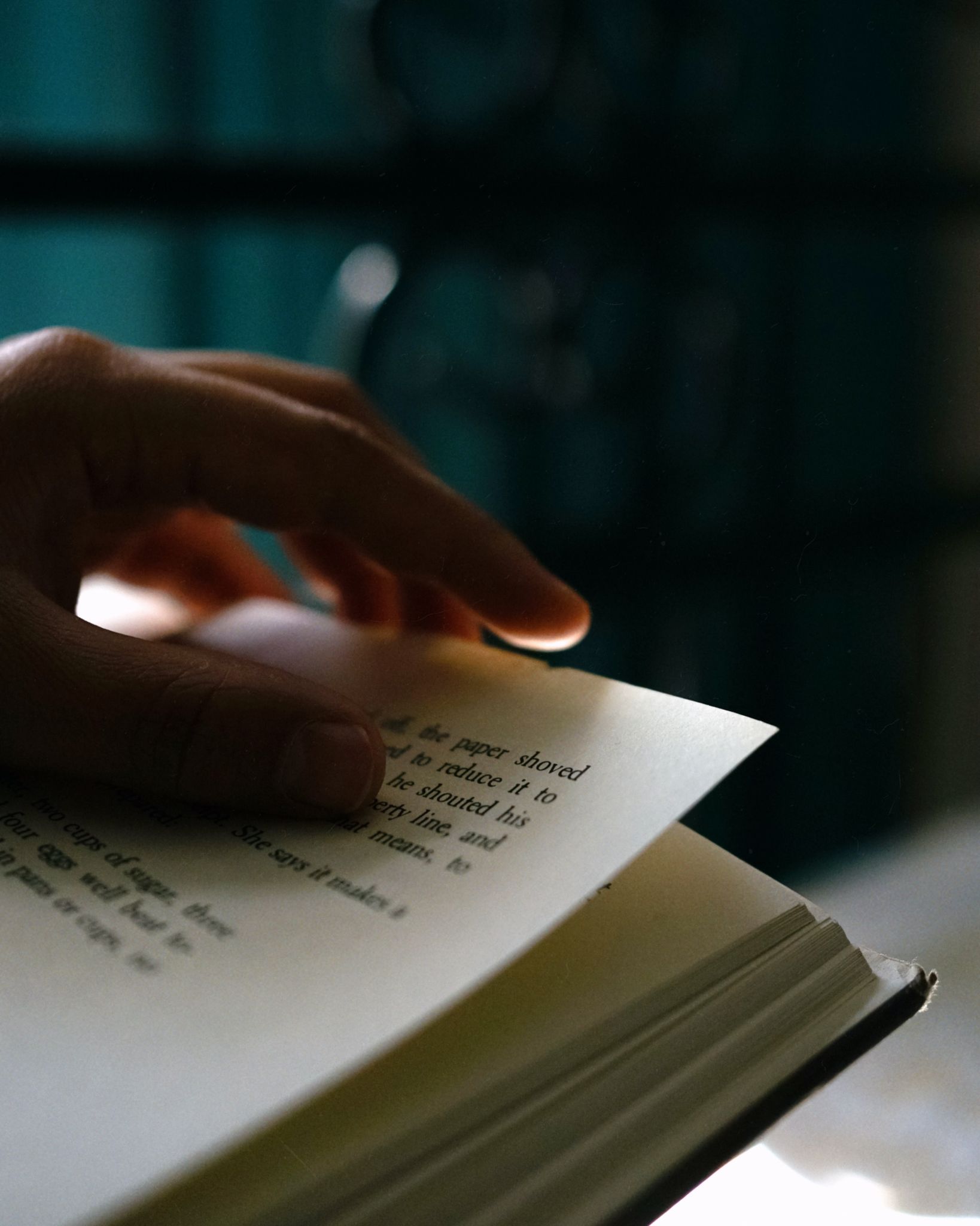 Close-up of a hand turning a page in a book, creating an intimate and peaceful scene.